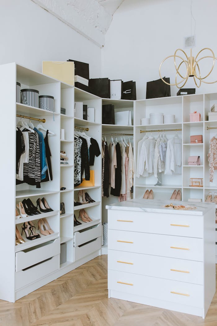 about-01 A stylish walk-in closet featuring luxury clothing, shoes, and accessories, with elegant shelving and chandeliers.